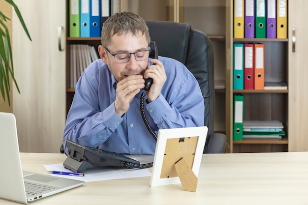 Office worker gossiping on the phone with his hand on the receiver