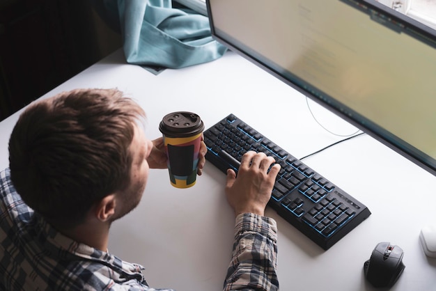 A office worker holding a paper cup with hot dring while doing the task