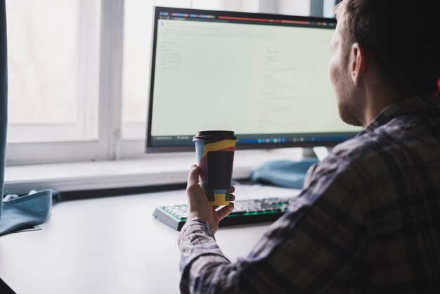 A office worker holding a paper cup with hot dring while doing the task