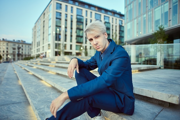 Office worker sits on stairs near building of business center