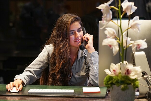 サラリーマンは職場で電話で話します。女性エージェント旅行代理店チェックアウト