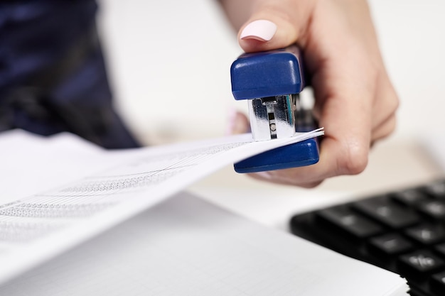 Office worker staples documents at office desk