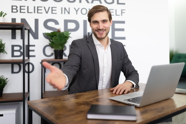 Office worker stretches out his hand while sitting in the office at the workplace