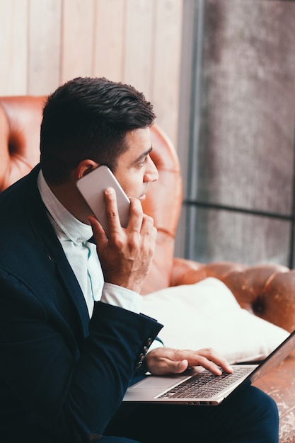 Office worker using laptop and smartphone.