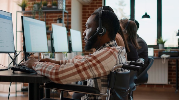 Office worker with handicap using headset to talk to clients at call center workstation. Sales consultant having telemarketing conversation with people on helpline at customer service.
