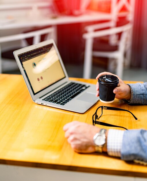 Office worker with laptop and coffee. Professional indoor businessman working with computer.