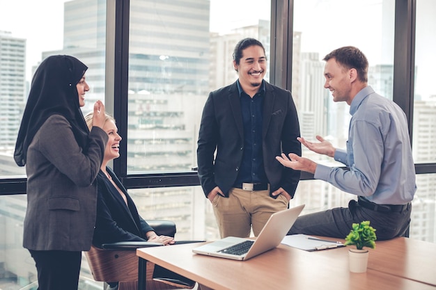 Office workers gather, exchange ideas, have fun chatting with laughter in the office during the relax time of working. Talk funny in the office of the employee group.