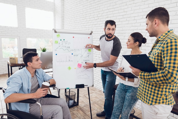 Office workers and man in a wheelchair discussing business