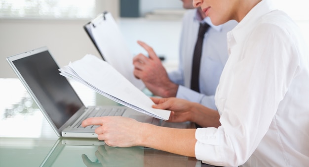 Office workers typing a report from blueprint documents