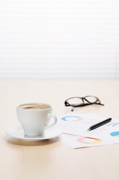 Office workplace with coffee supplies and reports