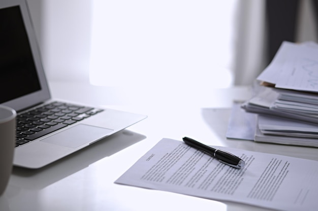 Office workplace with a laptop and contract document on the light reflecting table