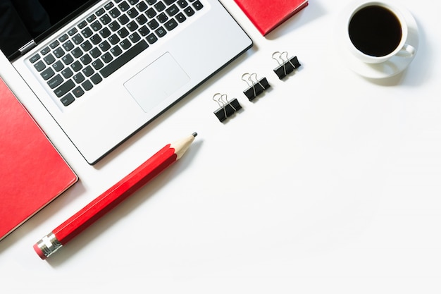 Office workplace with laptop, cup of coffee, red accessories