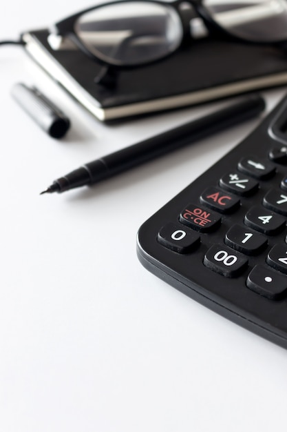 Office workplace with text space, black book, spectacles and calculator on white table