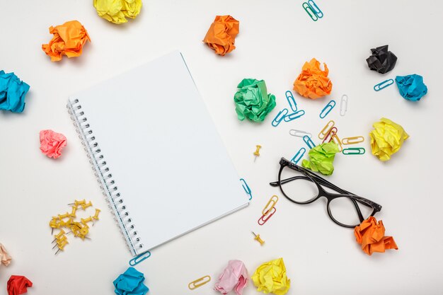 Office workspace with an empty notebook, crumpled paper