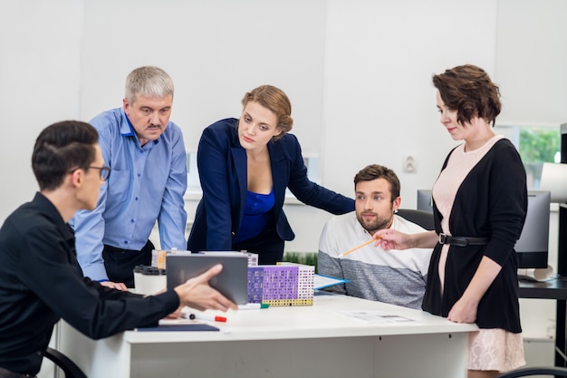 Office zakelijke bijeenkomst. Het team zit aan een tafel in een stralende witte open ruimte.