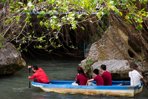 Officer local guide bring thai people travelers sit on boat through the cave travel visit in tham nam yen at Khao Chaison hot spring cold stream water ponds on March 12 2023 in Phatthalung Thailand