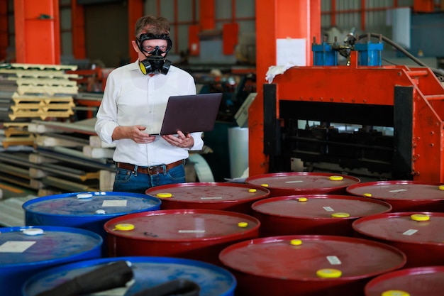 Officials from Department of Hazardous substances controlxAbureau is investigating the leak of hazardous chemical in chemical tank Man with protective mask and computer laptop in factory