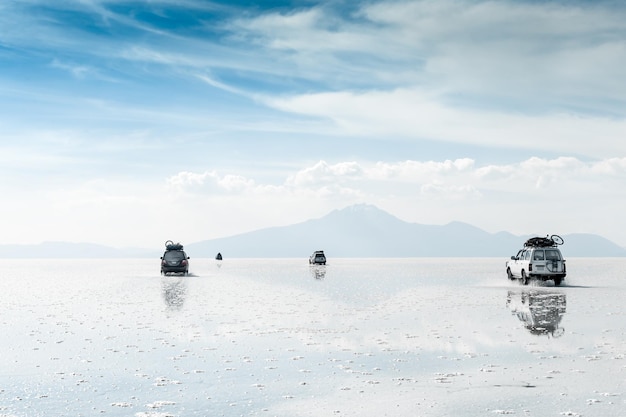 Автомобили, движущиеся по соленой равнине Салар-де-Уюни в Боливии