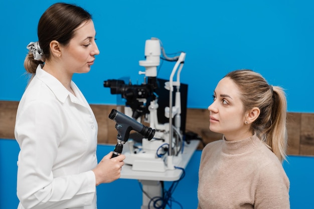 Oftalmoscopie Overleg met optometrist in medische kliniek Oogarts onderzoekt de ogen van vrouw met oftalmoscoop Oogheelkunde