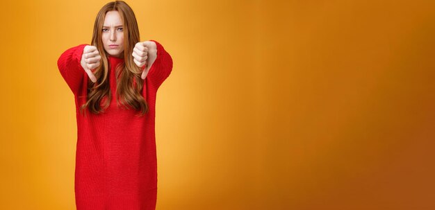 Oh no dislike portrait of upset and disappointed redhead female in red sweater frowning and pursing 