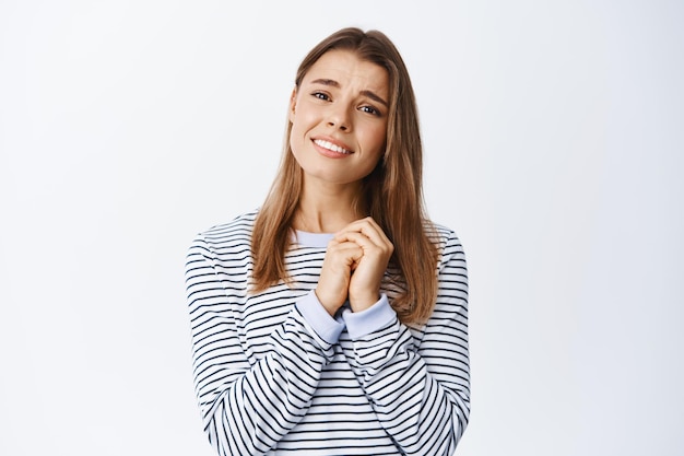 Oh so sweet. Touched young woman looking with love at something beautiful and adorable, tenderly gazing at something romantic, standing on white