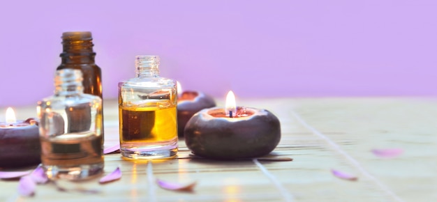 Photo oil bottles with candles light on a table on pink background