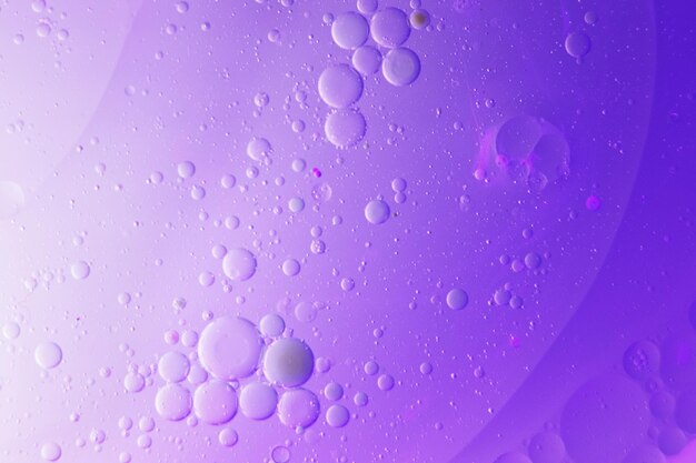 Oil bubbles close up circles of water macro abstract light purple background