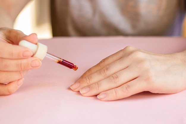 oil for cuticles The woman cares for hands and nails Woman applying oil from pipette to cuticle