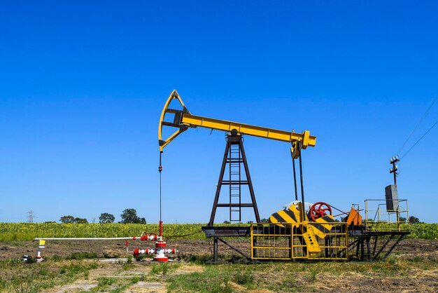 Oil drill on field against clear blue sky