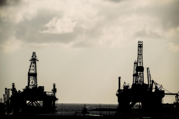 Photo oil drilling rig silhouette over a cloudy sky