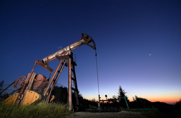 Oil field with petroleum pump jack under beautiful night sky