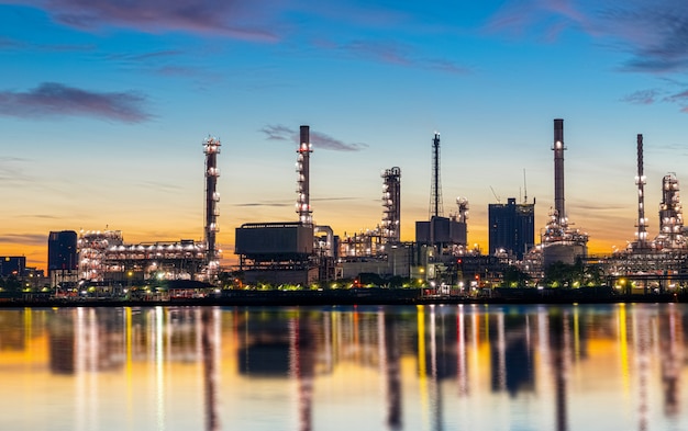 Oil and gas refinery industry plant with glitter lighting and sunrise in the morning