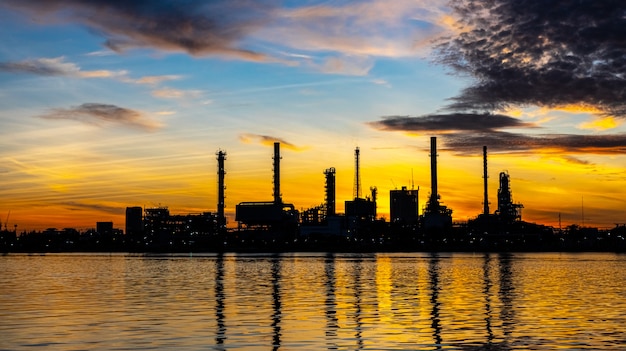 Oil and gas refinery industry plant with glitter lighting and sunrise in the morning