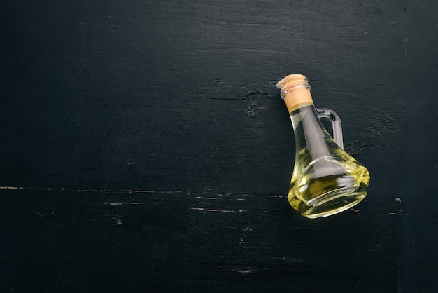 Oil in a glass jar Olive oil Top view On a black wooden background Free space for text