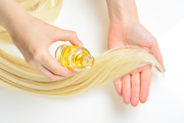 Foto trattamento per capelli con olio per donna con capelli biondi su sfondo bianco salone di bellezza spa cura dei capelli nel moderno salone spa