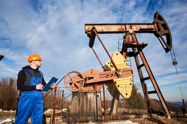 Uomo dell'olio che controlla il lavoro del martinetto della pompa del pozzo petrolifero