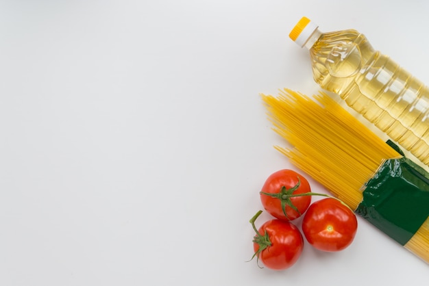 Oil, pasta and tomatoes on the white surface