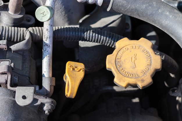 Oil probe and oil cap. Dusty details of a flat-four car engine compartment under the open hood.