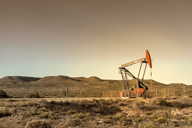 Photo an oil pump is seen in a field with mountains in the background