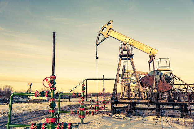 Oil pump jack and wellhead on an oil field. Mining and petroleum industry. Power generation concept. Oil and gas industry theme.