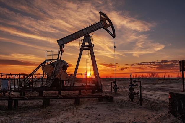 oil pump rig. oil and gas production. oilfield site. pump jack are running. drilling derricks for fossil fuels output and crude oil production. war on oil prices. global coronavirus covid 19 crisis.