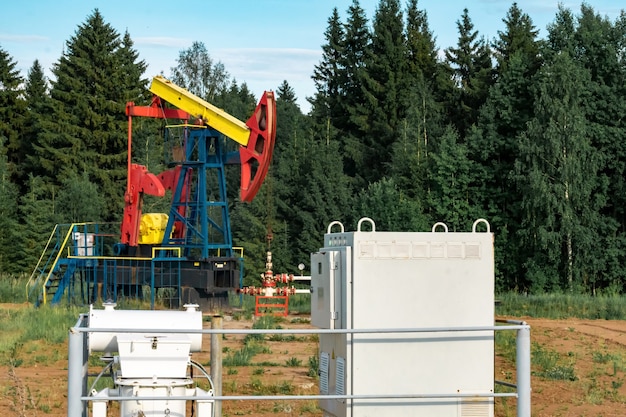 Oil pumping station with pumpjack in a clearing in the\
forest