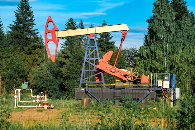 Oil pumping station with pumpjack in a clearing in the forest