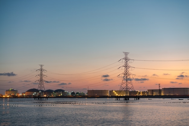 Oil refinery light river front reflection at twilight, industrial landscape background