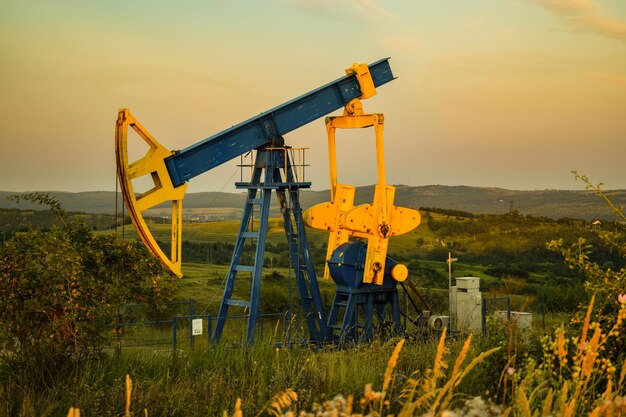 Photo oil rig on field against sky during sunset