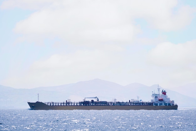 нефтяной танкер, плывущий по морю недалеко от побережья в солнечный день, концепция морской перевозки нефти и импортно-экспортной торговли