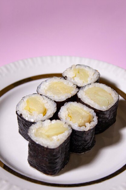 Photo oilfish maki roll with nori on white plate on pink