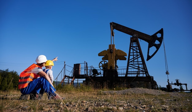 Oilman showing little boy at oil extraction station