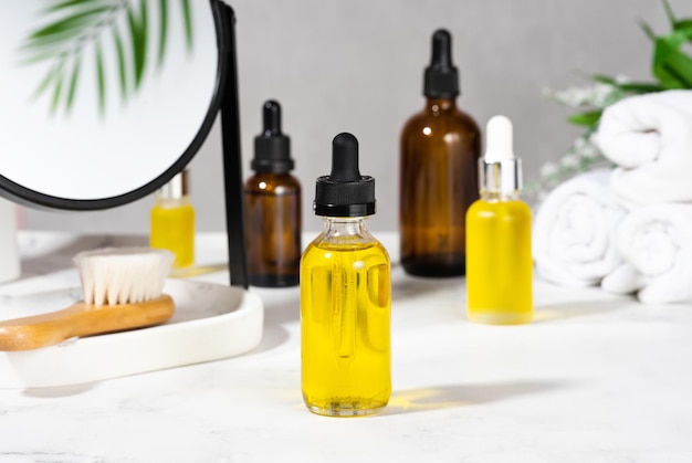 Oils bath brush towel and mirror on the cosmetic table in the bathroom A set of organic cosmetics in glass bottles with dropper for skin and hair care The concept of home care in the bathroom