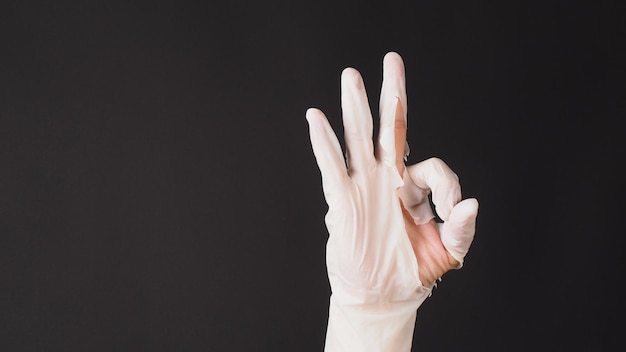 Photo ok hand sign and wear latex glove on black background